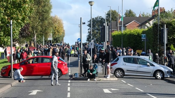 Protesters gather on Garvaghy Road with two cars blocking a parade route